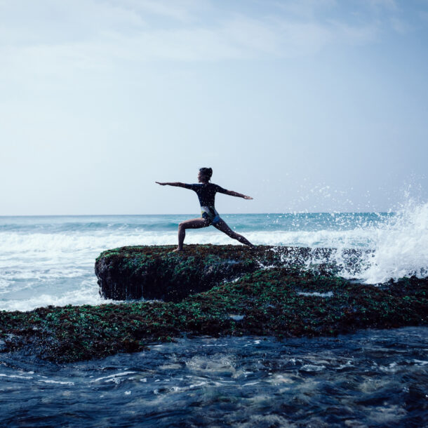 Healthy woman does yoga along a rocky beach