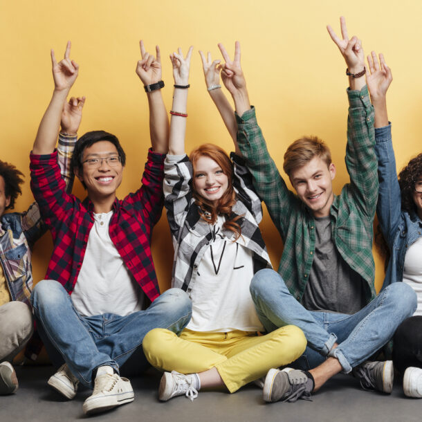 Diverse group of young individuals with their arms in the air celebrating success.