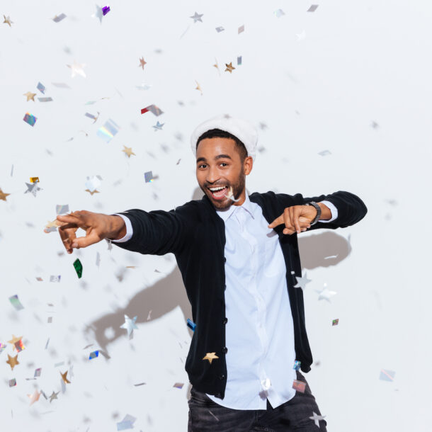 Joyful young man wearing a Santa hat dancing on a white background