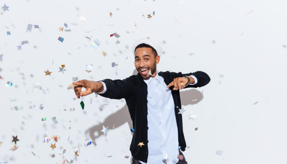 Joyful young man wearing a Santa hat dancing on a white background