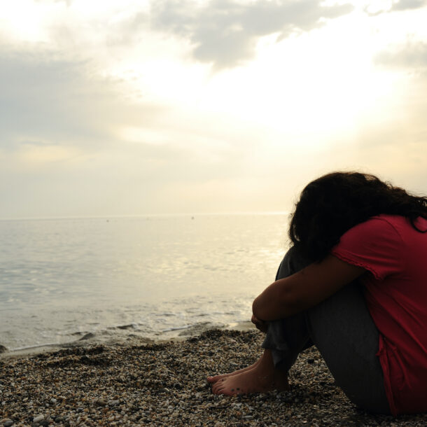 Lonely, sad woman on the beach sitting