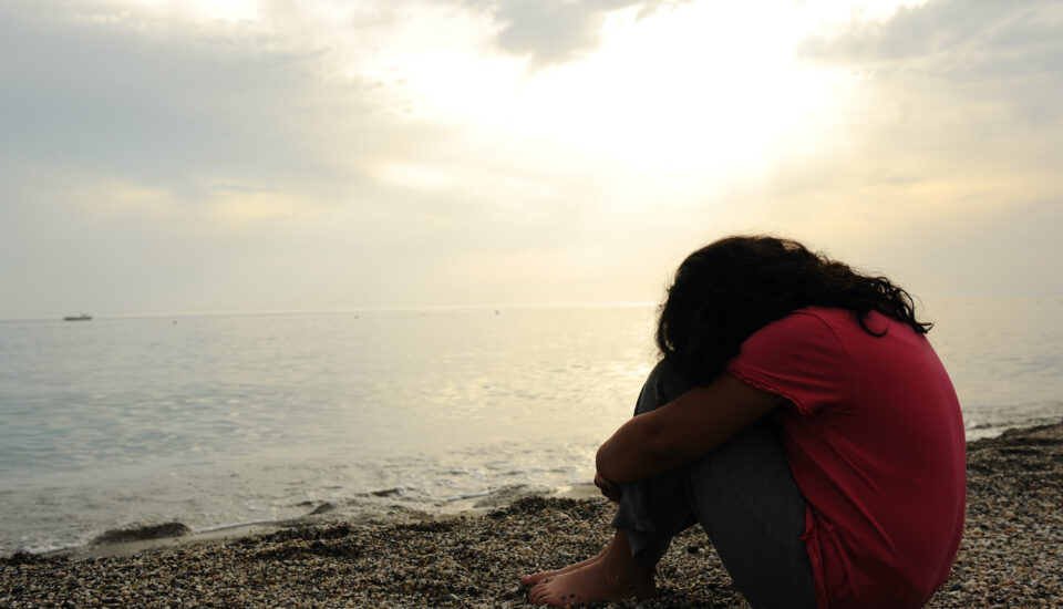 Lonely, sad woman on the beach sitting