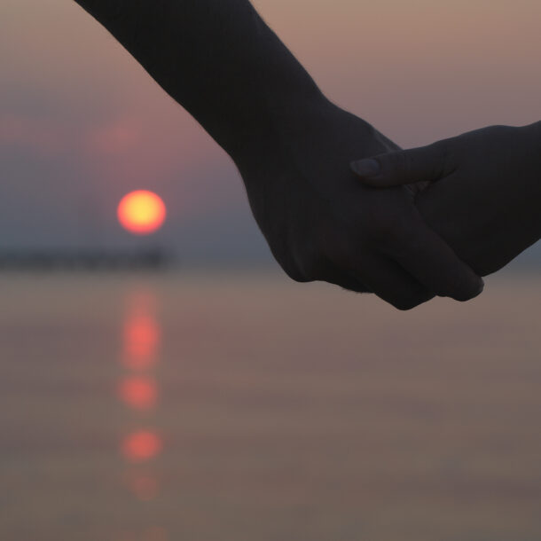 A couple holding hands at sunset.