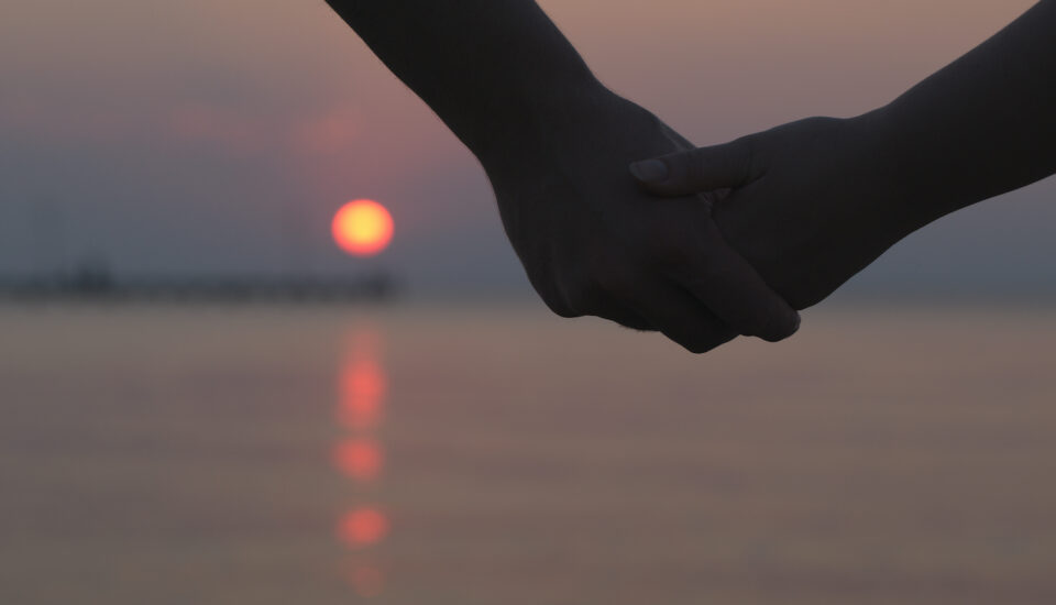 A couple holding hands at sunset.