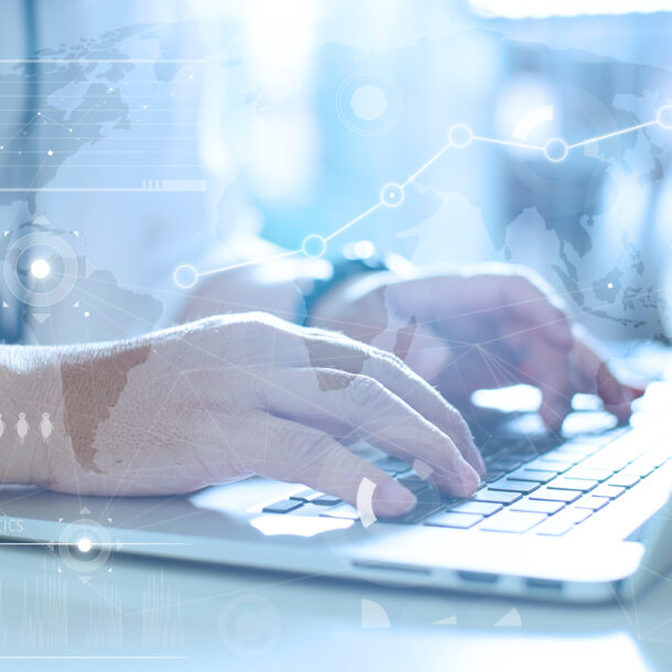 A man's hands typing on a laptop with a technological graphic.