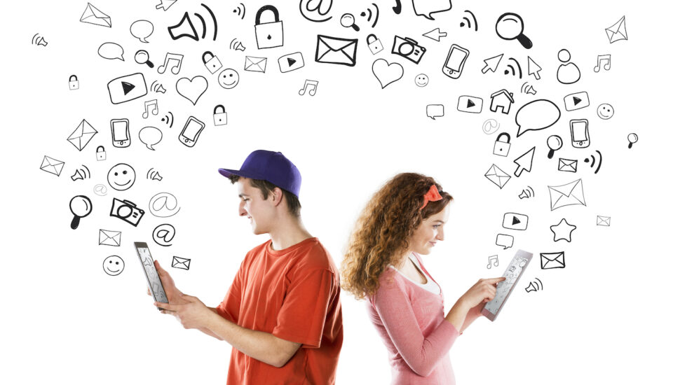Young couple with tablets and social media icons floating around them.
