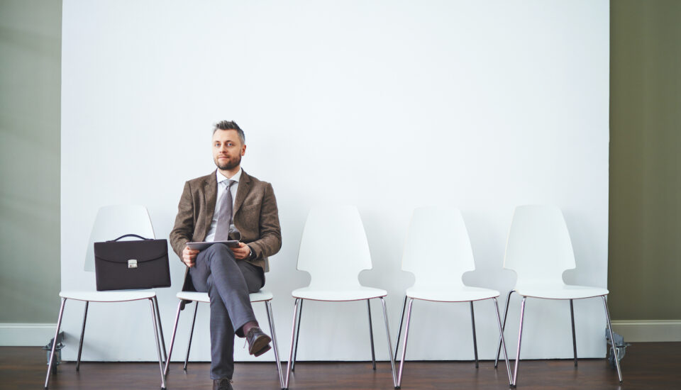 A man in a suit is sitting and waiting for an interview.