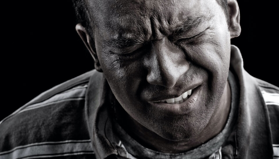 Black and white photo of a man In extreme anguish or pain.