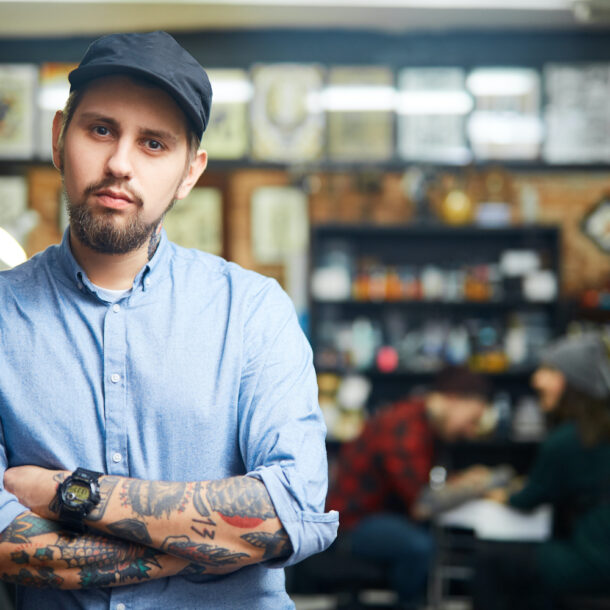 A tattooed man standing alone, contemplating something.