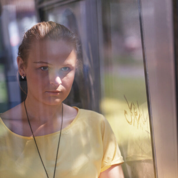 Young woman in yellow rides the bus alone looking out the window.