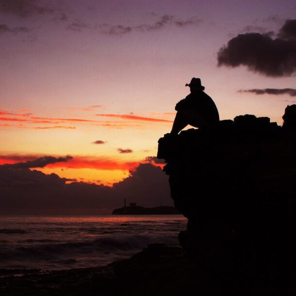 Silhouette of man in hat on the background of sunset at sea.