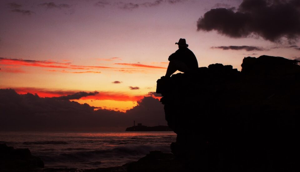 Silhouette of man in hat on the background of sunset at sea.