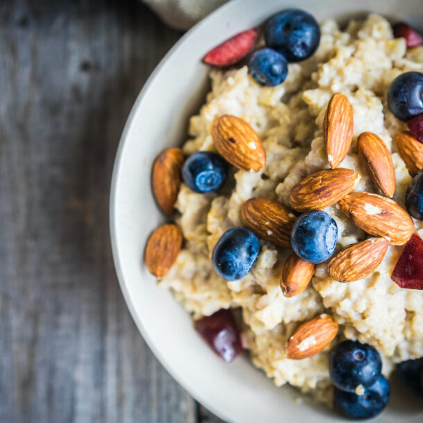 A bowl of oatmeal with berries and nuts on a table.