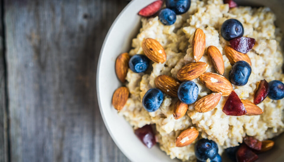 A bowl of oatmeal with berries and nuts on a table.