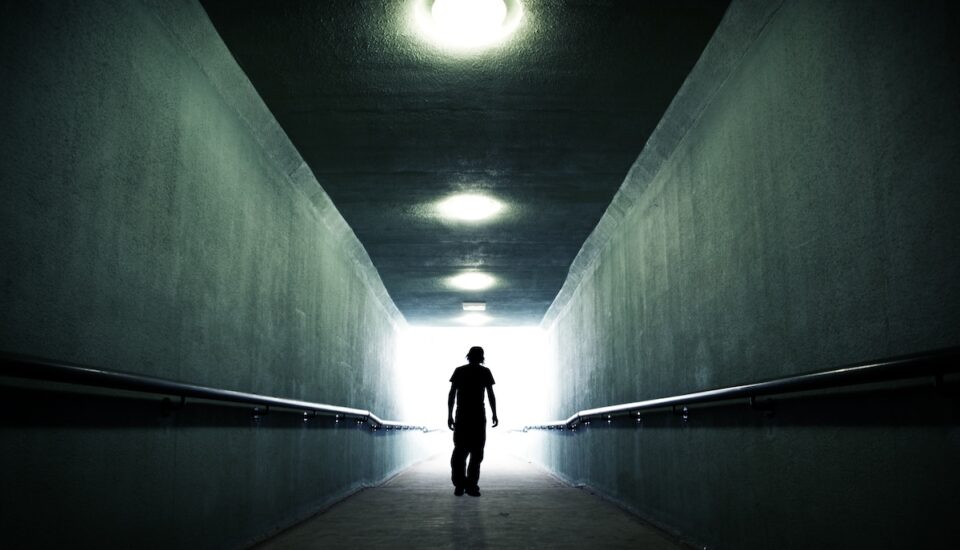 Youth walking through a dark tunnel and into the light.