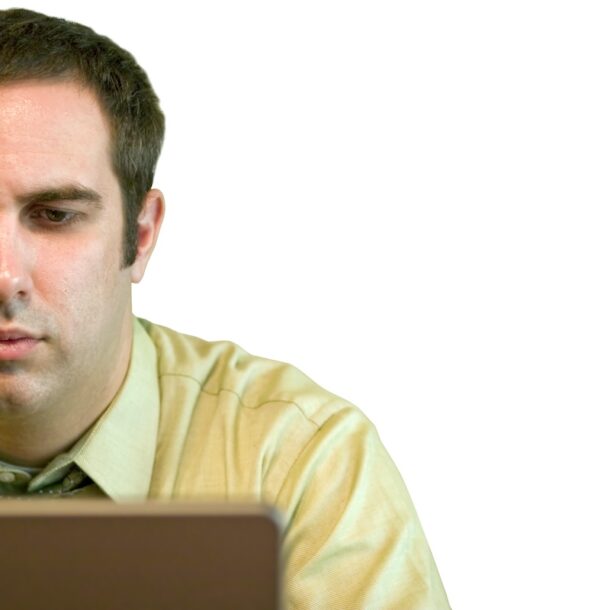 A young business man working on a laptop with a white background. home on his laptop.