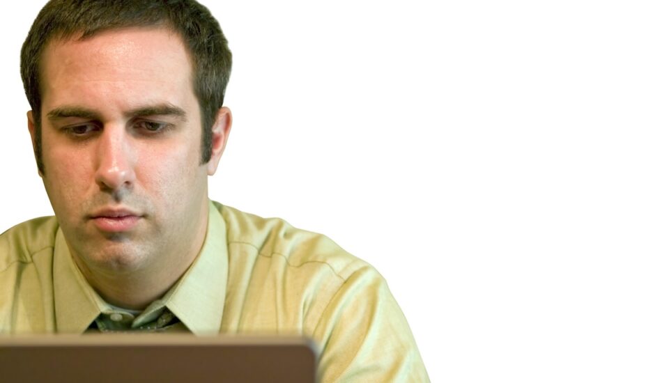 A young business man working on a laptop with a white background. home on his laptop.