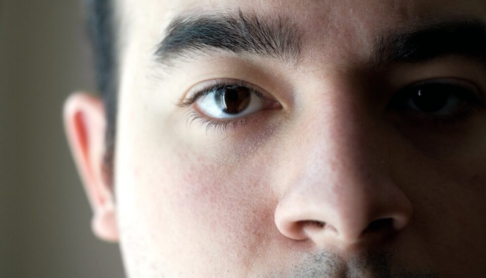 A closeup of the eye on a young man with a serious look on his face.