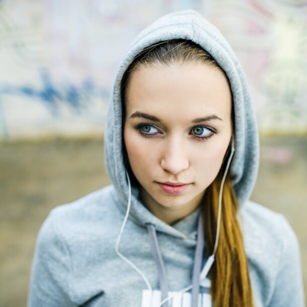 Teenage girl with hood on listening to music.