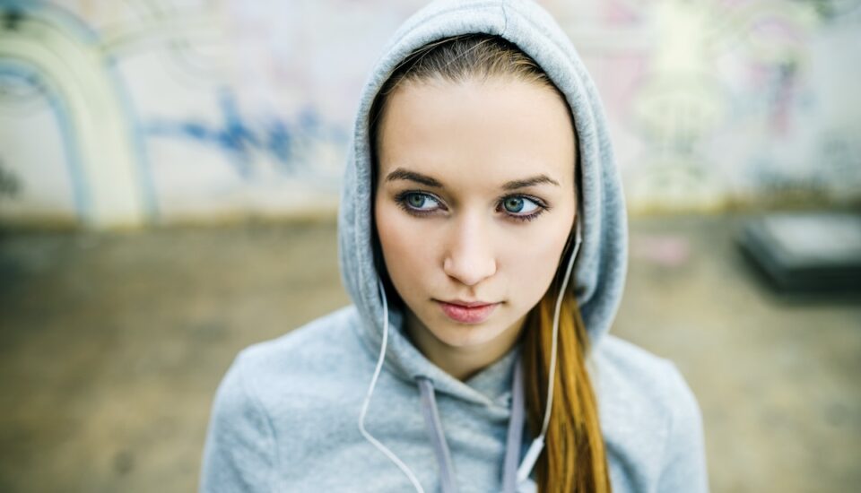 Teenage girl with hood on listening to music.