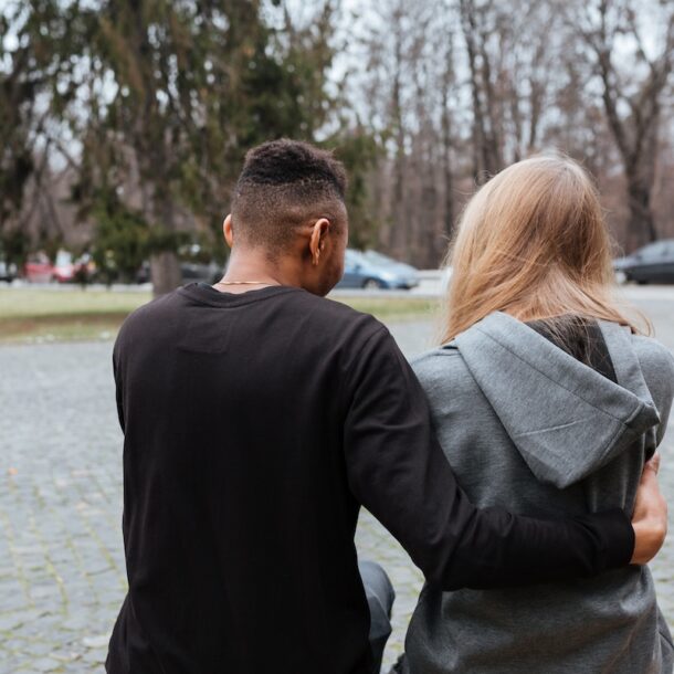 Young multiethnic couple sitting and hugging outside.